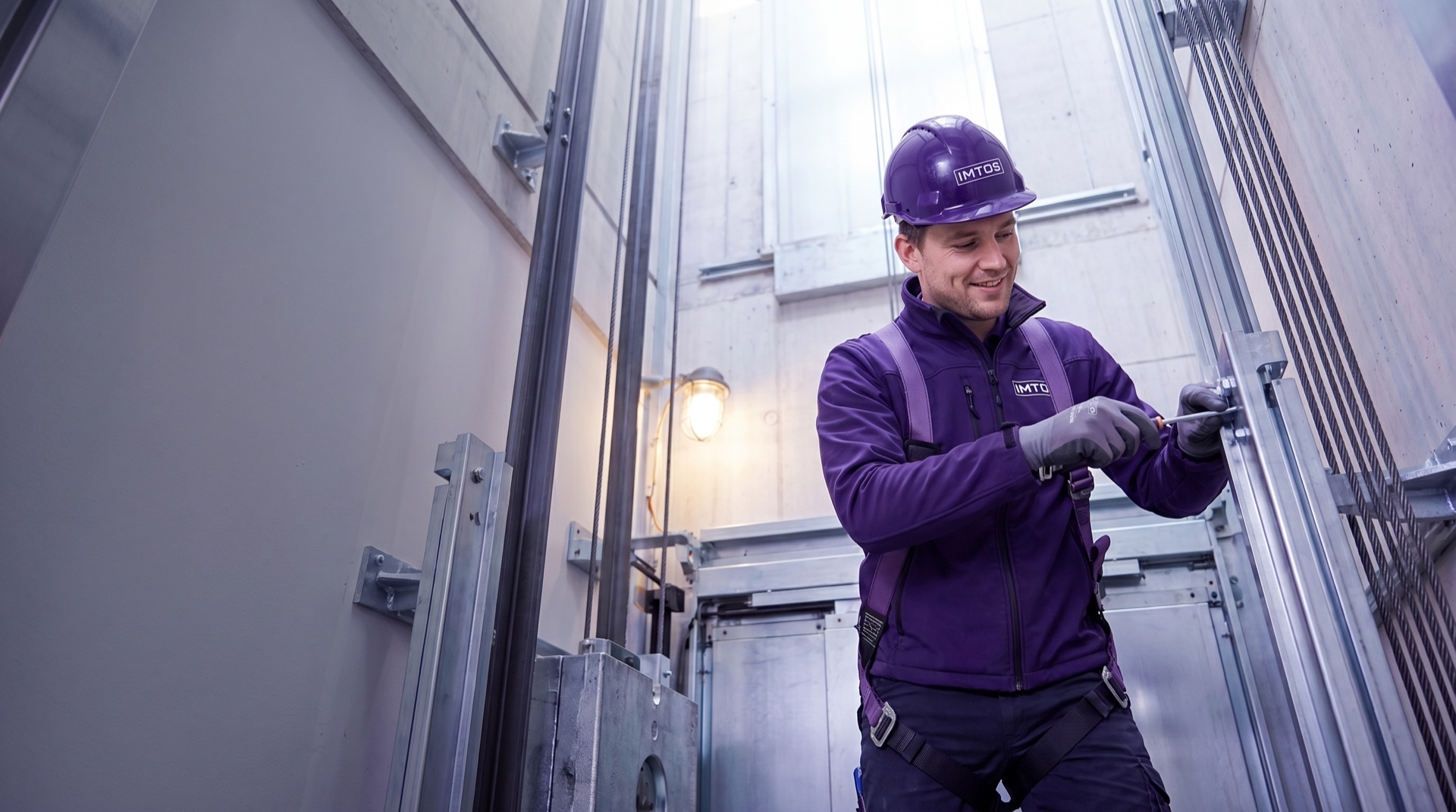 IMTOS-servicemonteur in bedrijfskleding aan het werk in een liftschacht